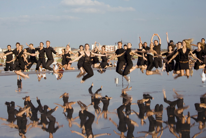 Group of dancers caught in mid jump with their reflection in water